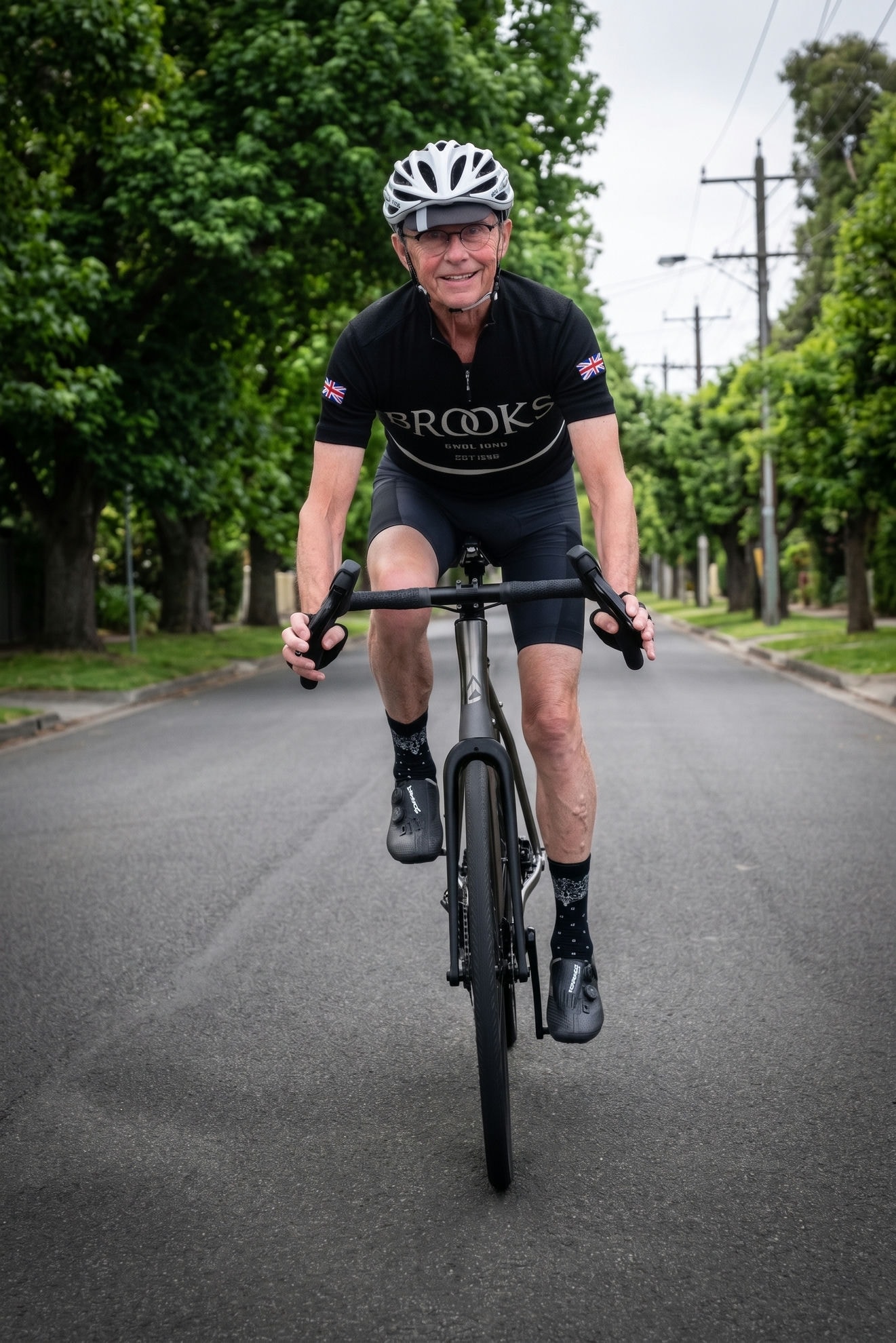 A rider on an Auren titanium road bike on a tree-lined street