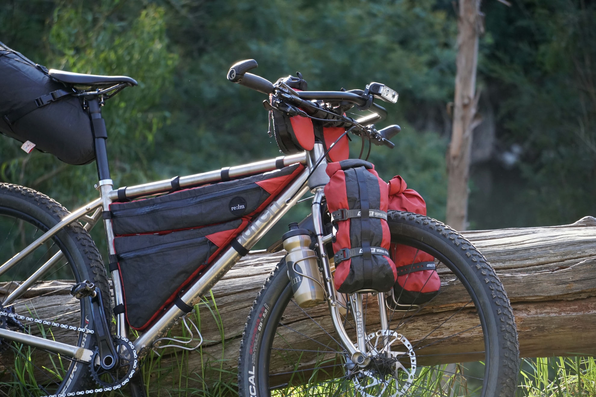 Loaded Auren titanium bikepacking bike leaning on a log