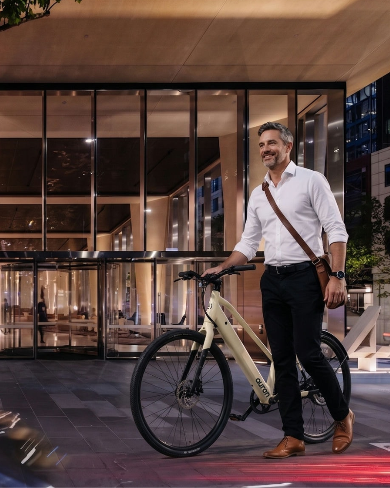 Man in a white shirt walking an Auren EV5 outside an office building