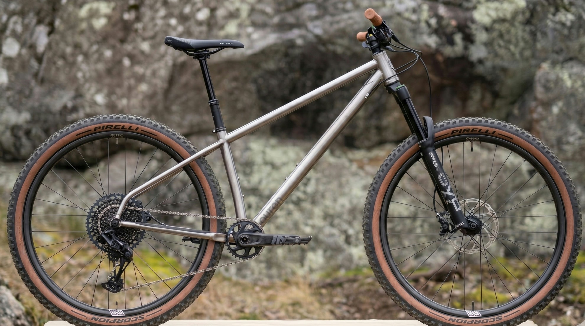 An aggressive Auren titanium hardtail built for Pilot Bike Co, leaning on rocks