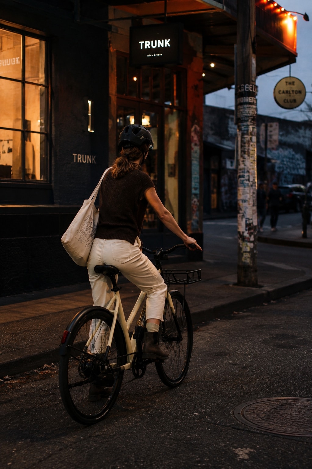 Woman riding a Sand Auren EV5 away down a Collingwood street at night