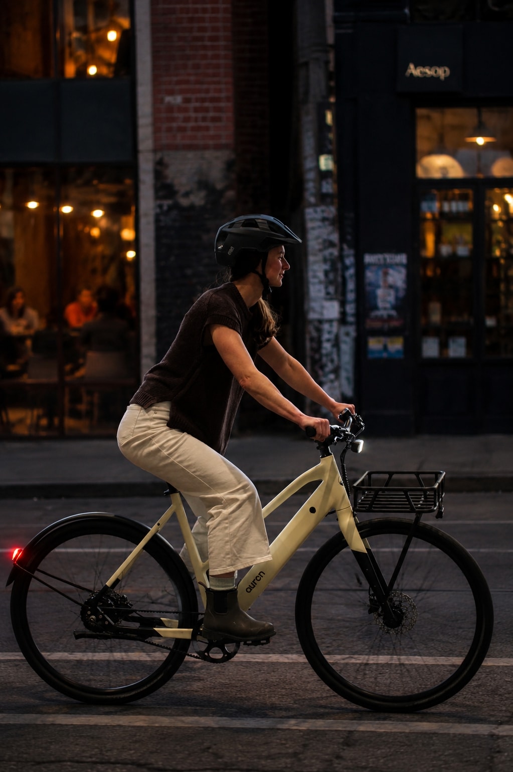 Woman riding an Auren EV5 through Collingwood at night