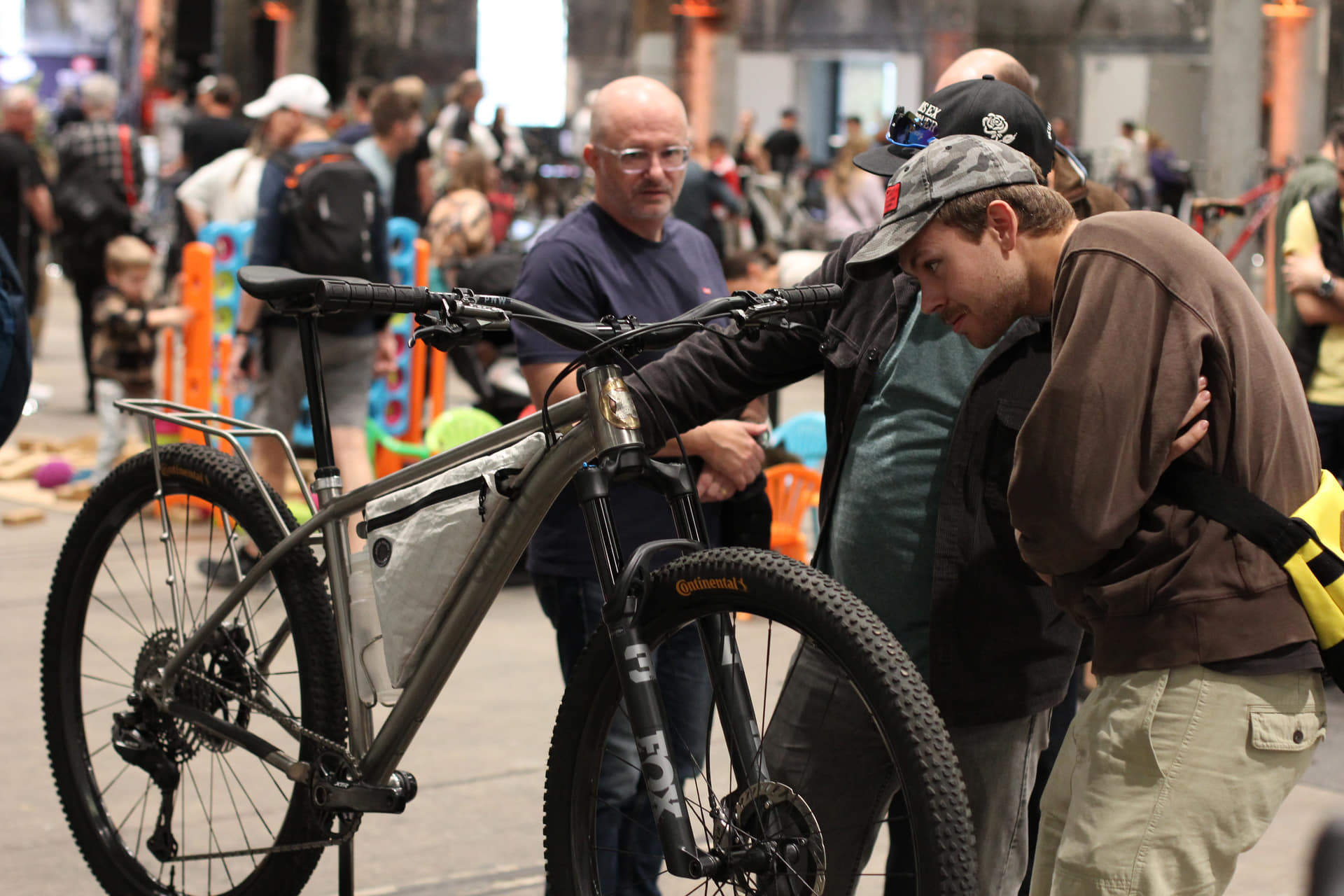 Visitors looking over an Auren titanium hardtail with a custom titanium rack and frame bag at the Spoken bike show
